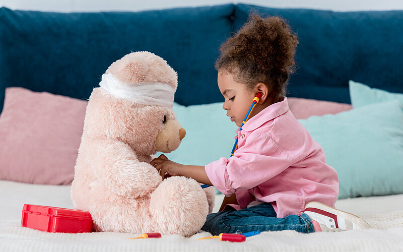 Ein kleines Mädchen spielt mit ihrem Teddybären Arzt.
