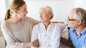 Eine Seniorin erhält am Krankenbett Besuch von ihrer Familie.