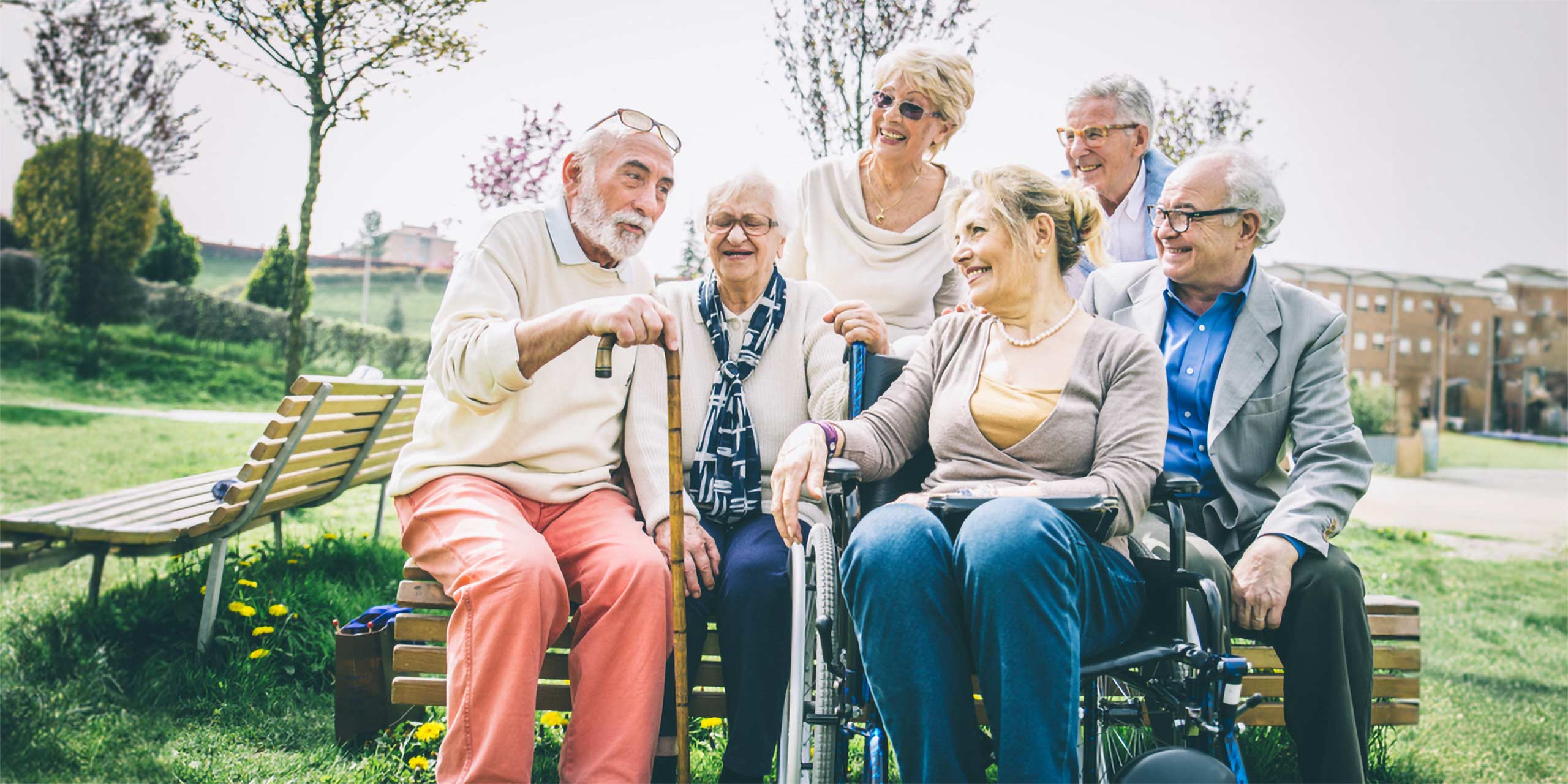 Außenaufnahme einer ausgelassen fröhlichen Gruppe von Senioren auf einer Parkbank